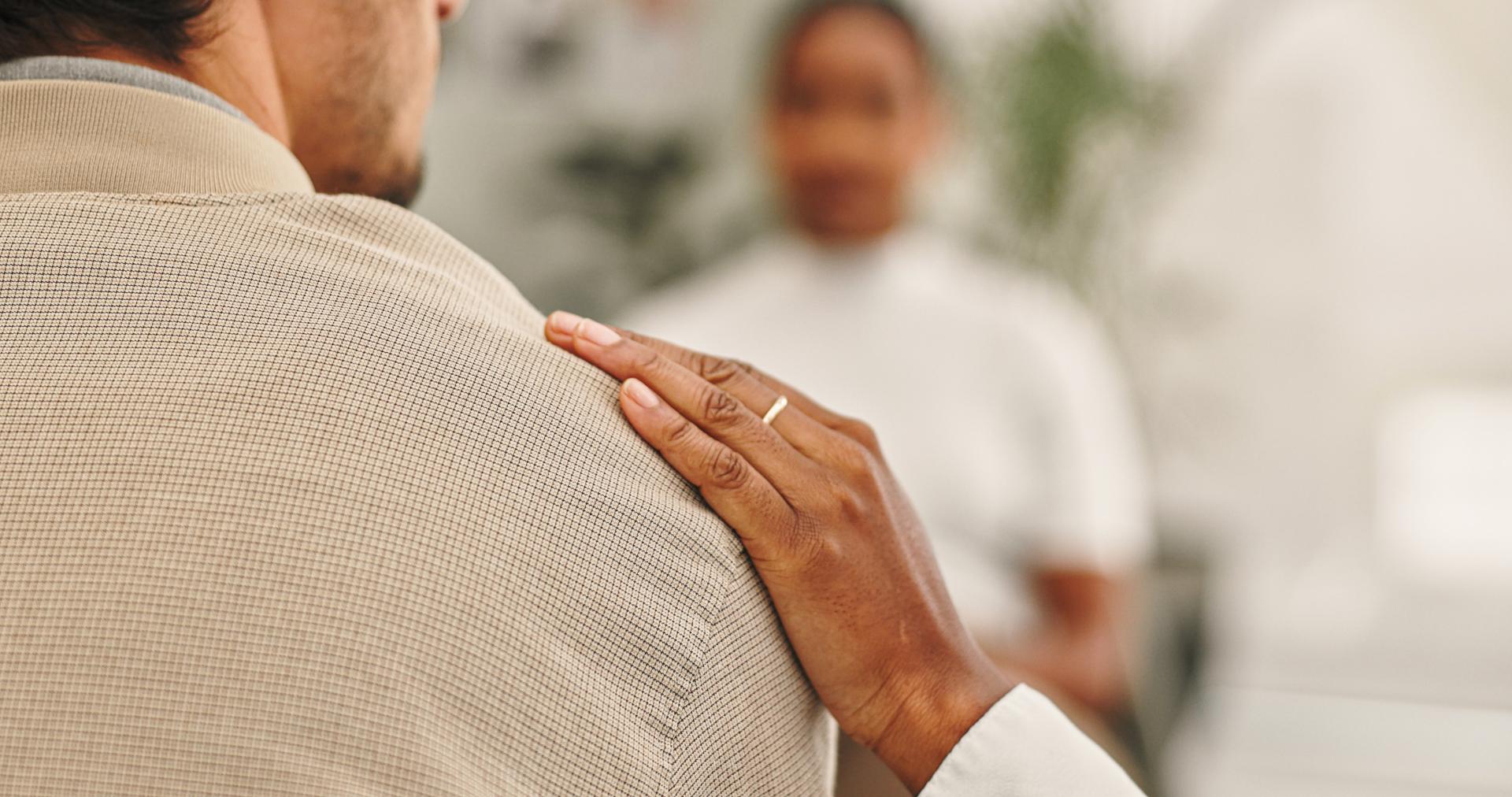 Someone placing a gentle hand on a persons shoulder